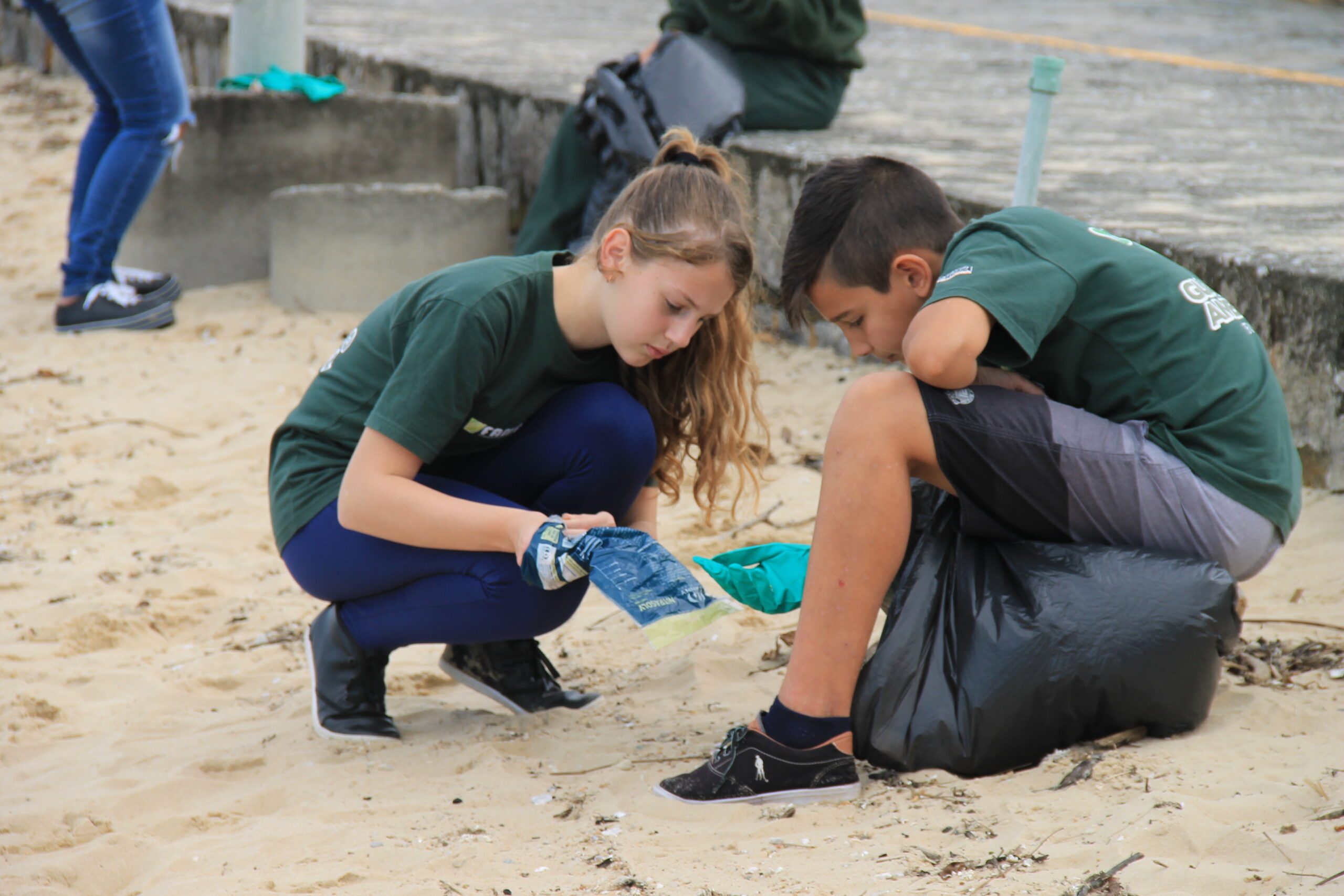 Alunos realizando limpeza de praia em ação do projeto Guardião Ambiental